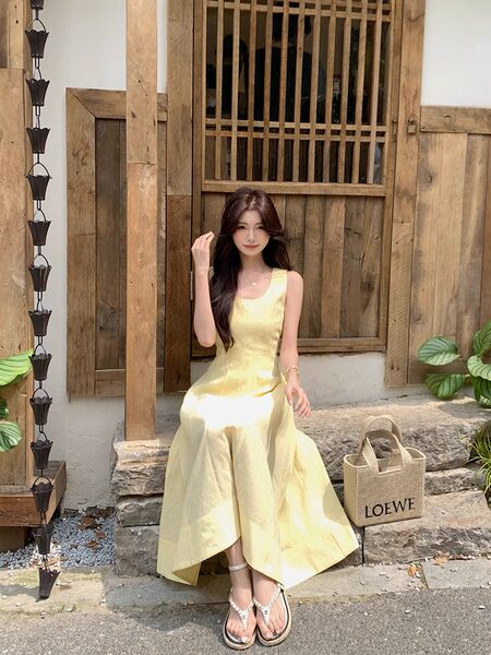 Woman wearing a pale yellow sleeveless dress outdoors