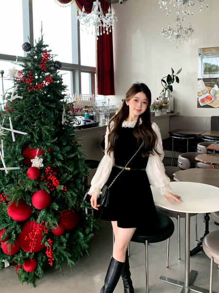 Woman wearing a black dress with white blouse sleeves in a festive cafe setting