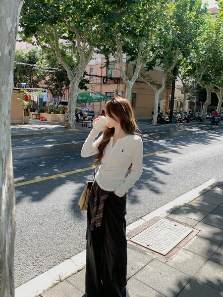 Woman wearing a white long-sleeve top with black wide-leg pants outdoors