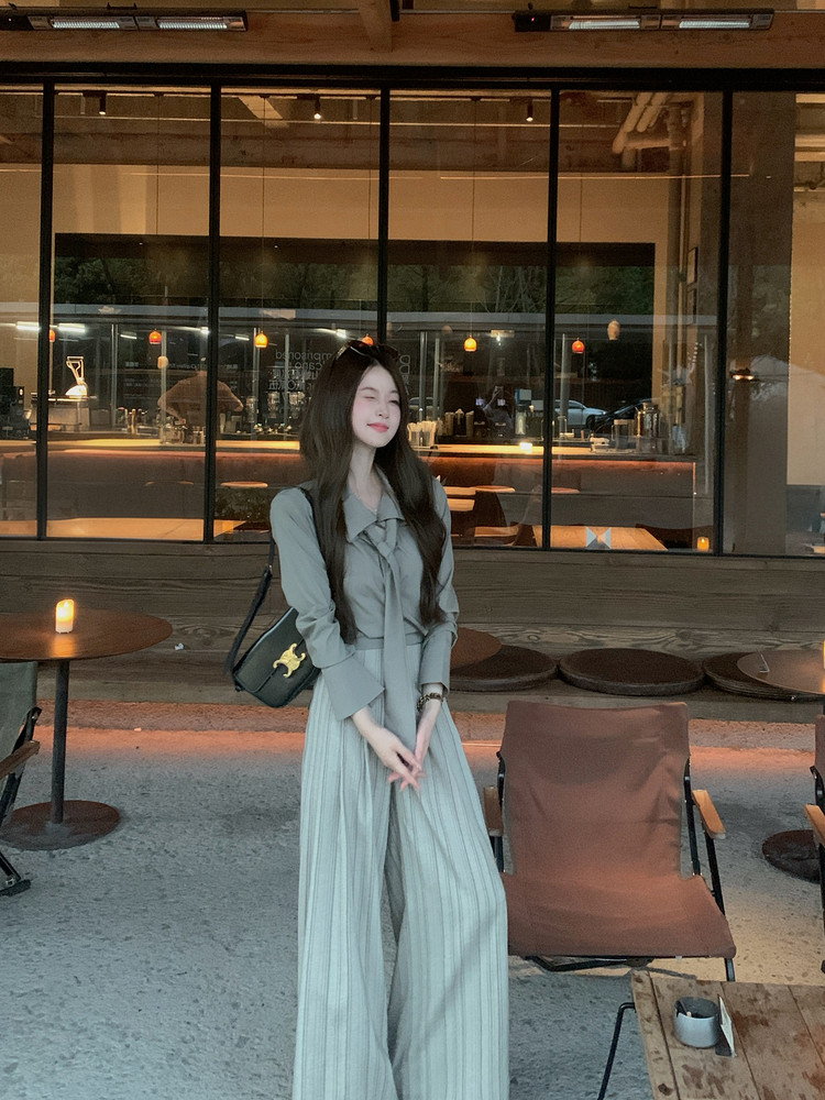 Woman wearing a gray blouse and wide-leg pleated pants in a cafe setting
