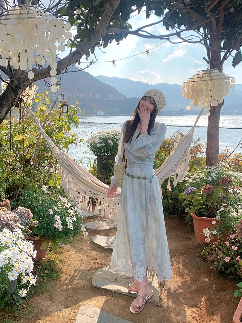 Woman wearing a light blue flowy dress outdoors by the water