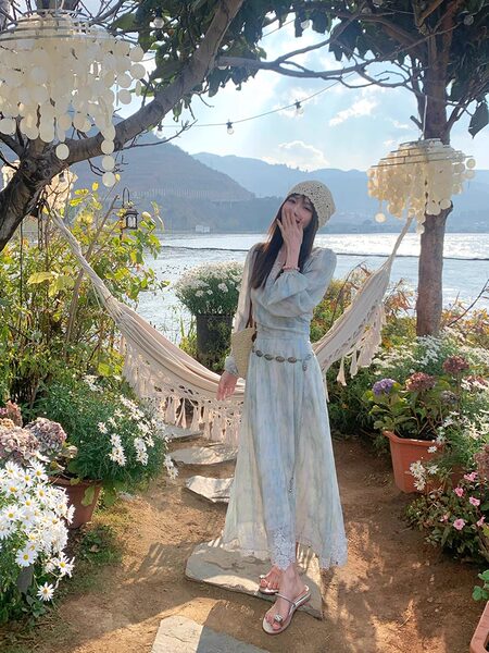 Woman wearing a light blue flowy dress outdoors by the water