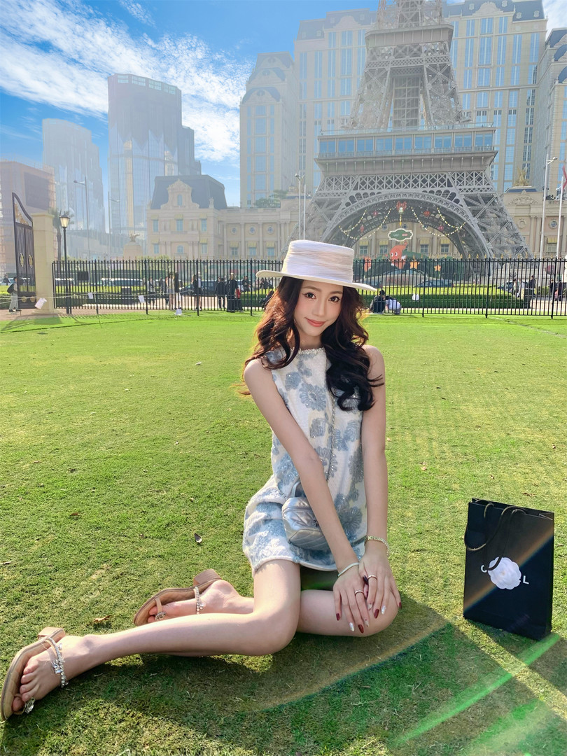 Woman wearing a light blue floral sleeveless dress with a white hat and sandals outdoors