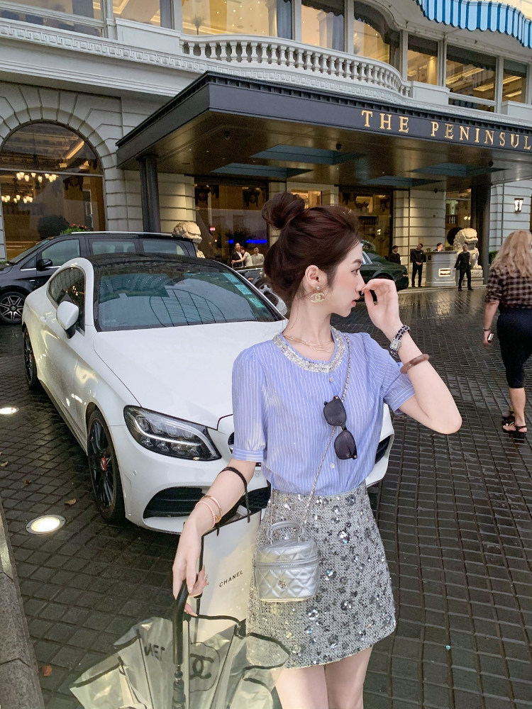 Woman wearing a light blue striped top with a silver sequined mini skirt on a city street