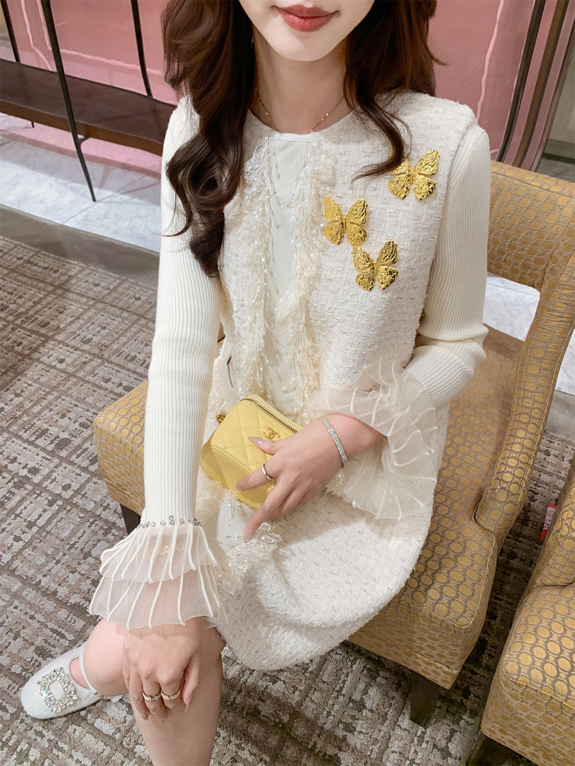 Woman modeling a white textured dress with gold butterfly embellishments
