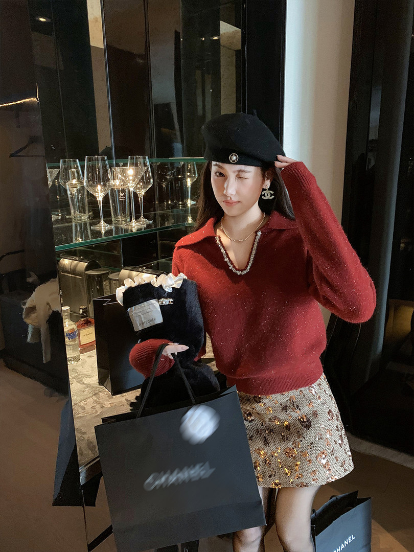 Woman wearing a red knit sweater, sequined mini skirt, and black beret in a luxury indoor setting