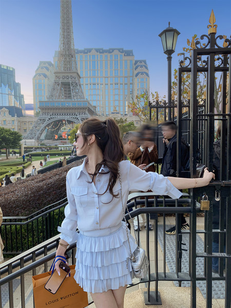 Woman wearing a white blouse and tiered mini skirt outdoors near the Eiffel Tower