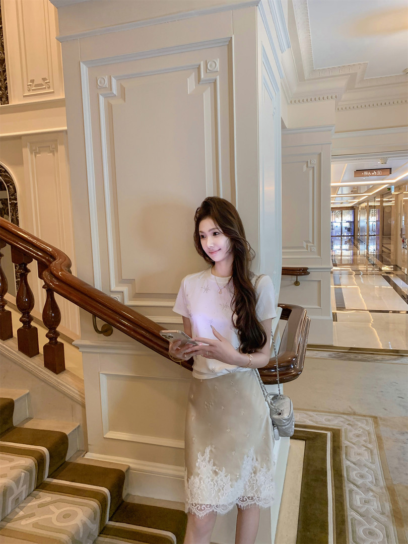 Woman wearing a white embellished top with a beige lace skirt