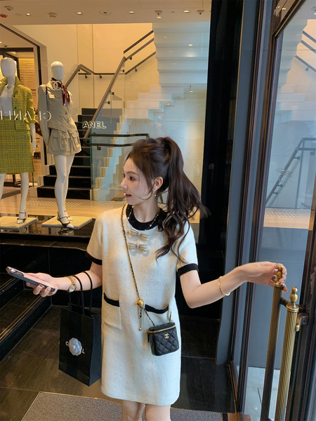 Woman wearing a cream and black short dress in a boutique storefront