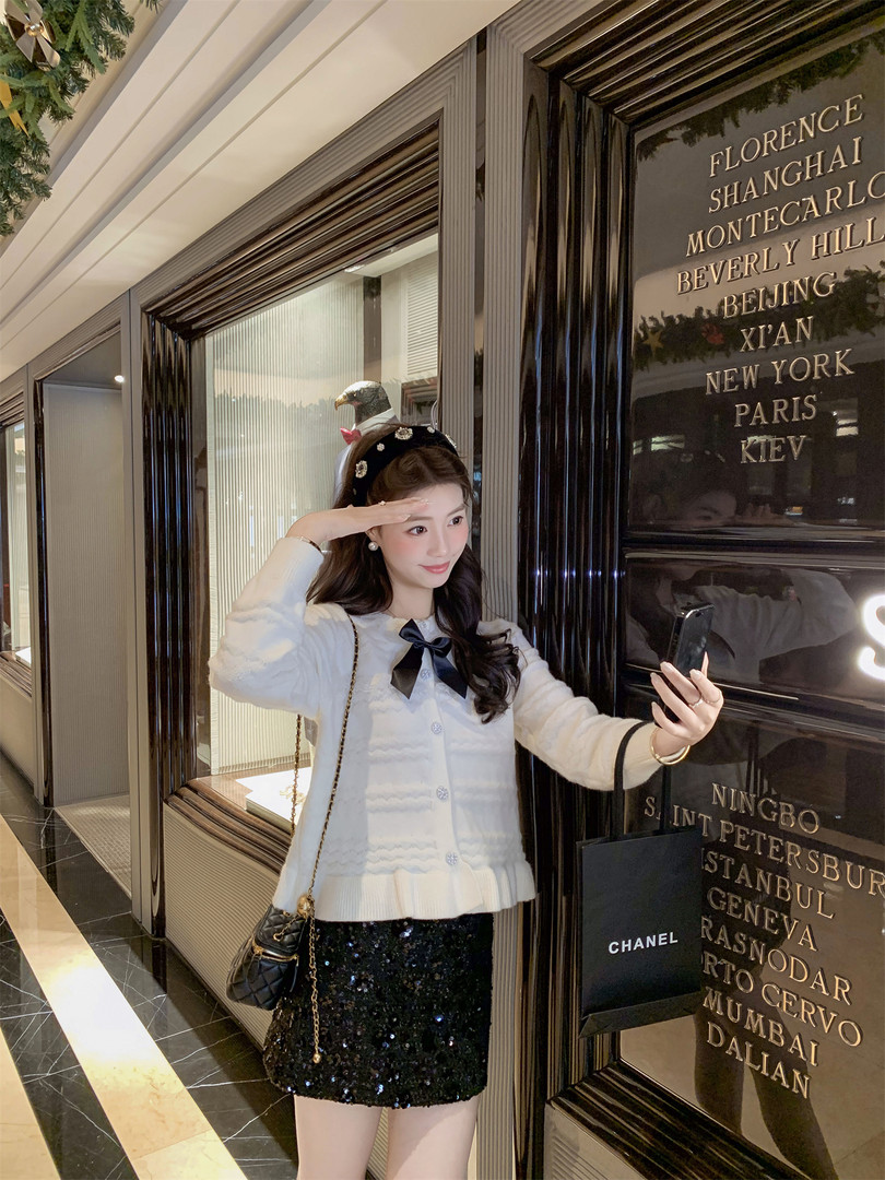 Woman wearing a white cardigan and black sequined skirt in a luxury interior