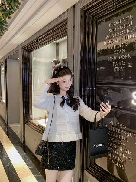 Woman wearing a white cardigan and black sequined skirt in a luxury interior