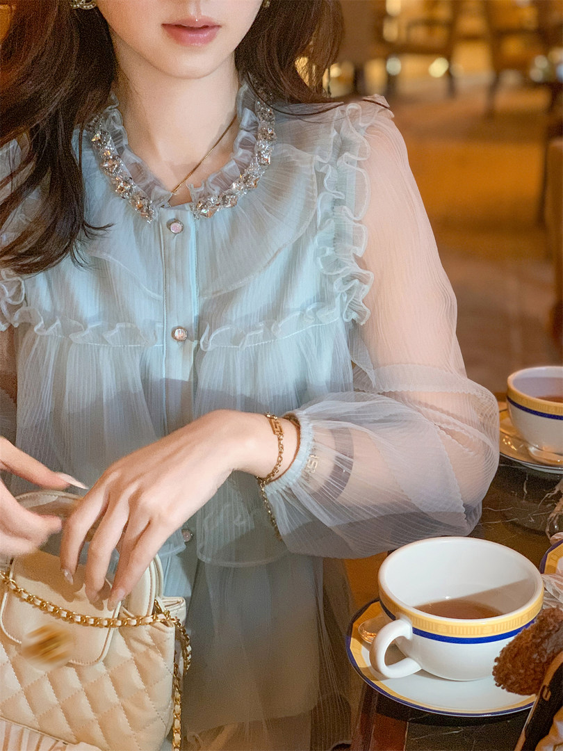 Light blue sheer ruffled blouse worn by a model