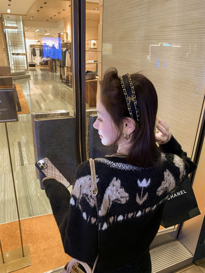 Woman wearing a black patterned knit sweater and chain headband in a boutique