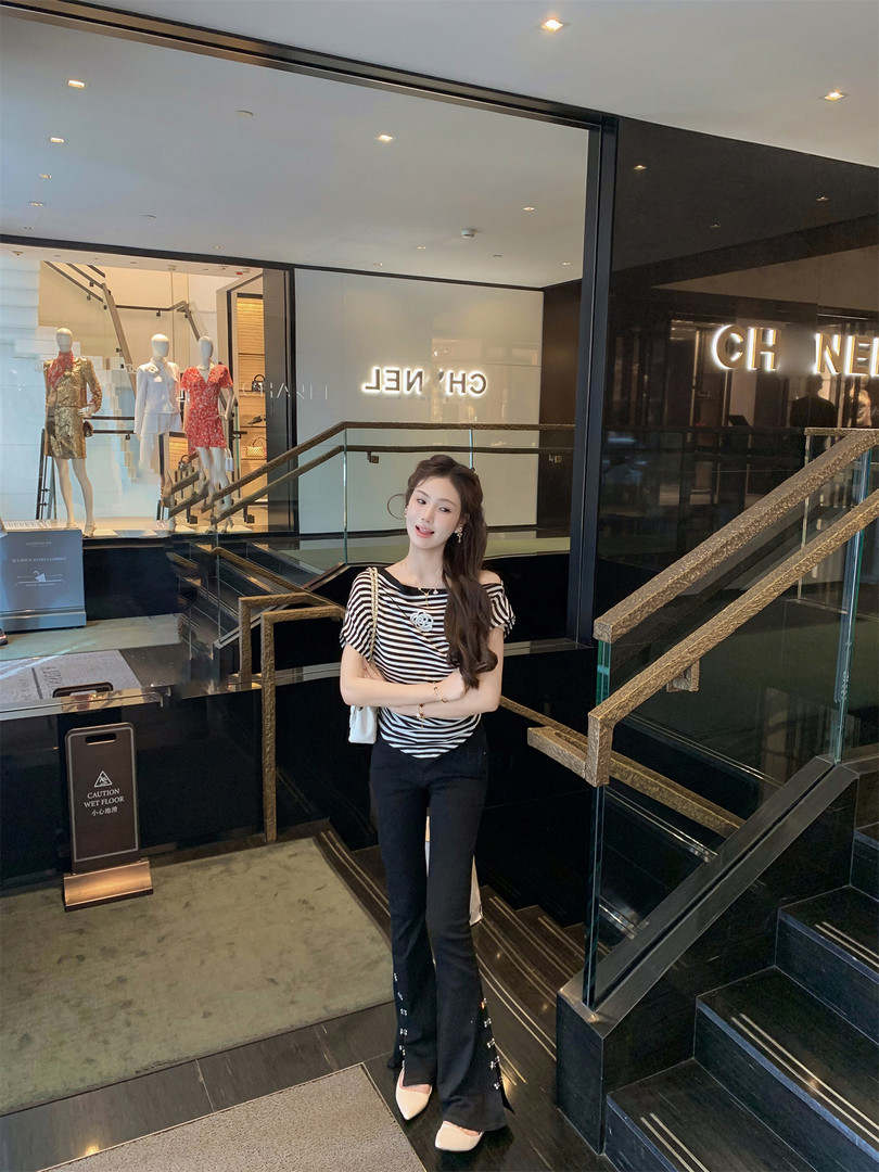Woman wearing a black-and-white striped top with black flared pants in a fashion store