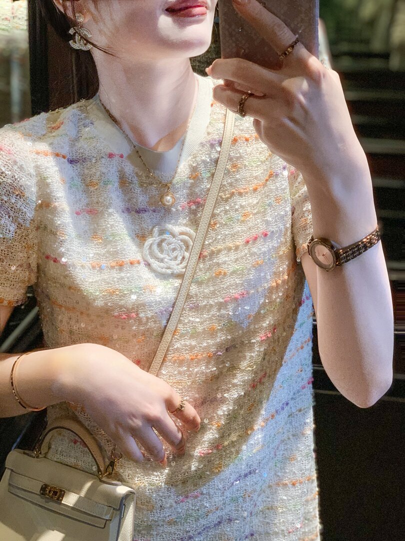 Woman wearing a cream textured sequined top with a pearl detail