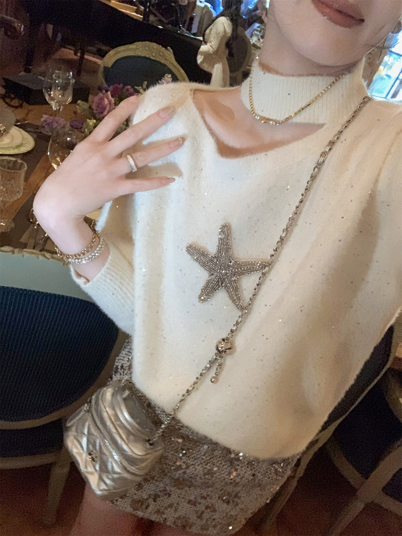 Woman wearing a white embellished knit sweater with silver accessories and a sequined skirt