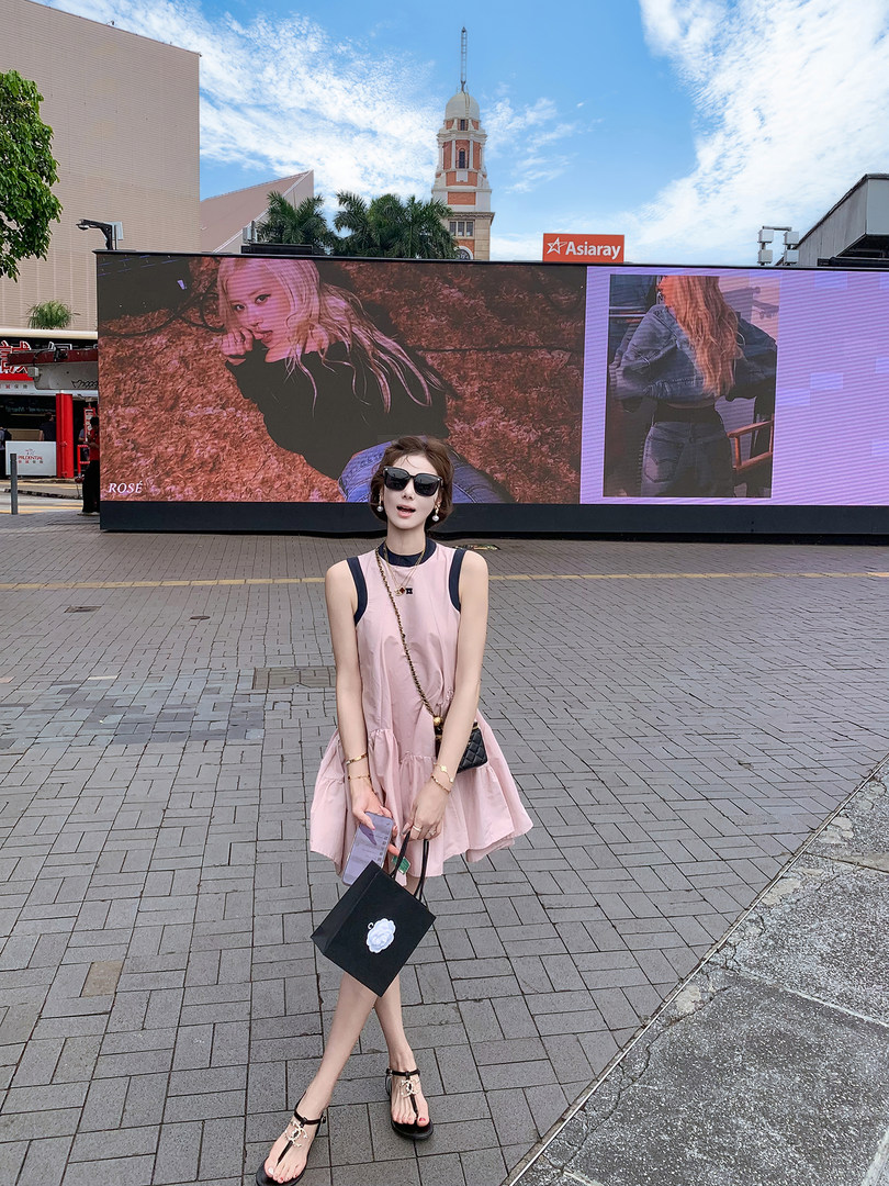 Woman wearing a light pink sleeveless dress and black sandals outdoors