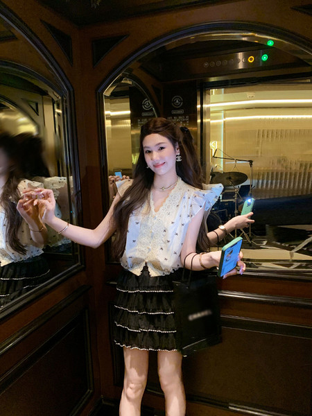 Woman wearing a white ruffled blouse and black tiered skirt outfit
