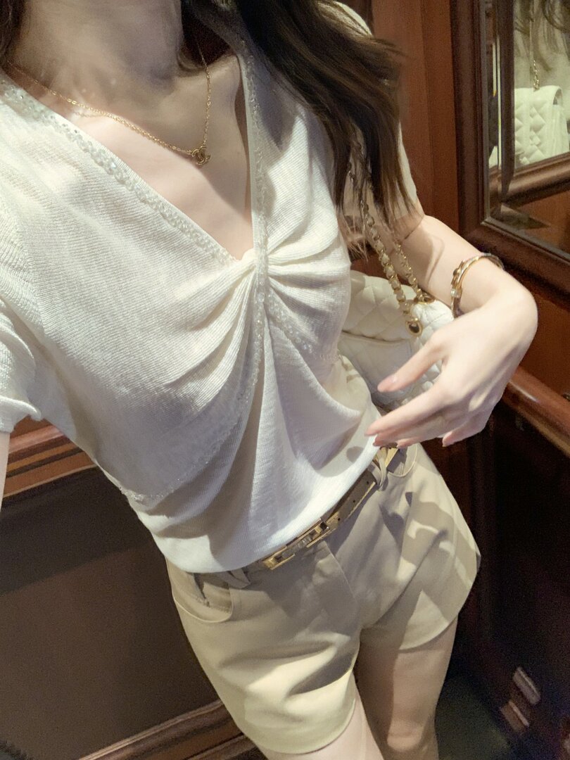 Woman wearing a white draped sleeveless top with beige shorts