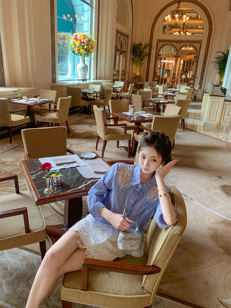 Woman wearing a blue striped blouse and white lace skirt in a restaurant