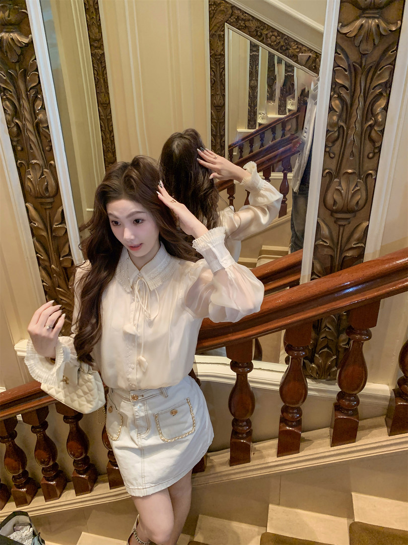 Woman wearing a white ruffled blouse and white skirt with a quilted handbag