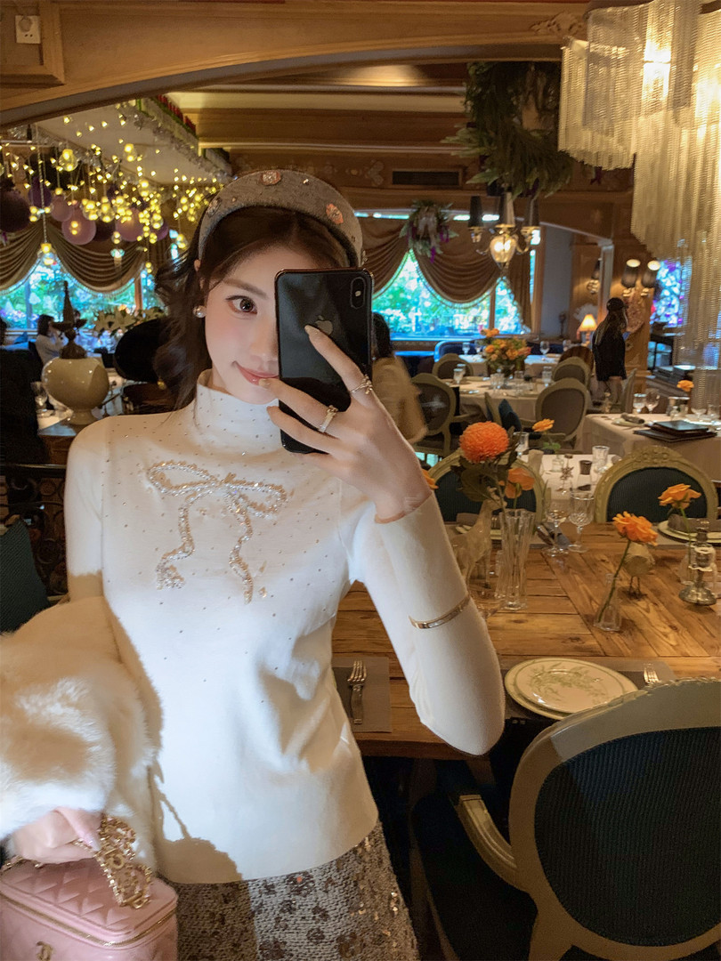 Woman wearing a white embellished long-sleeve top and sequined skirt in a restaurant