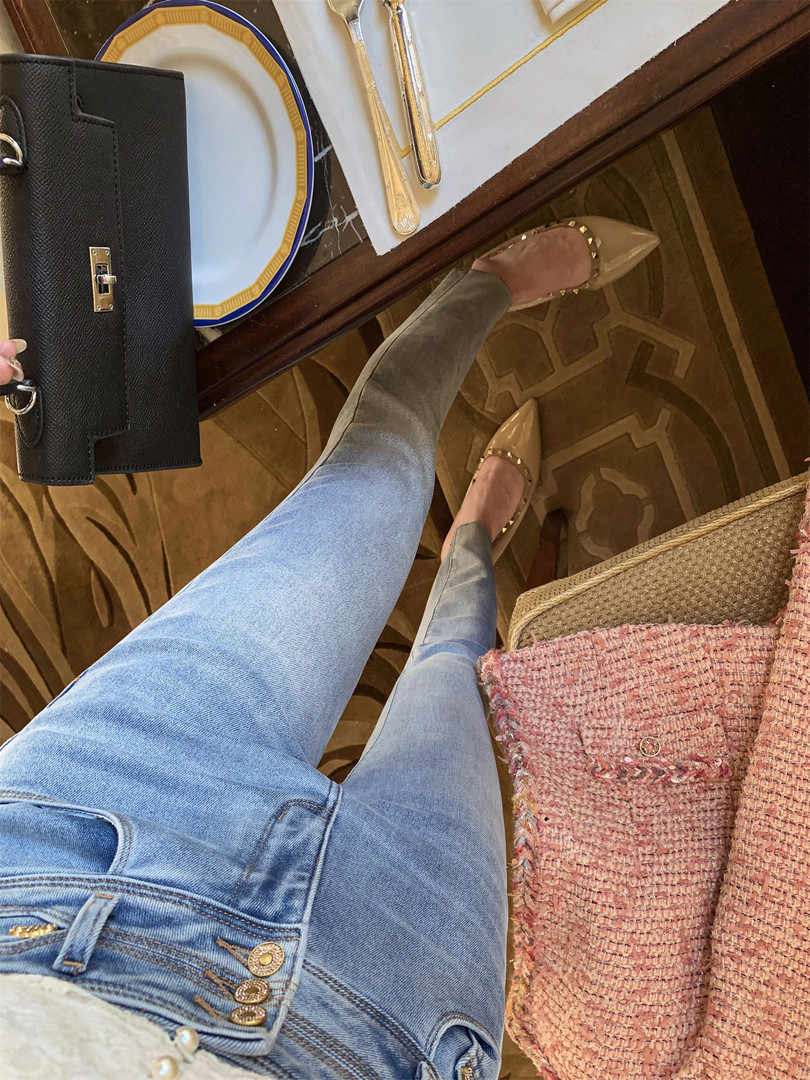 Outfit photo showing blue jeans, beige studded flats, and designer handbags