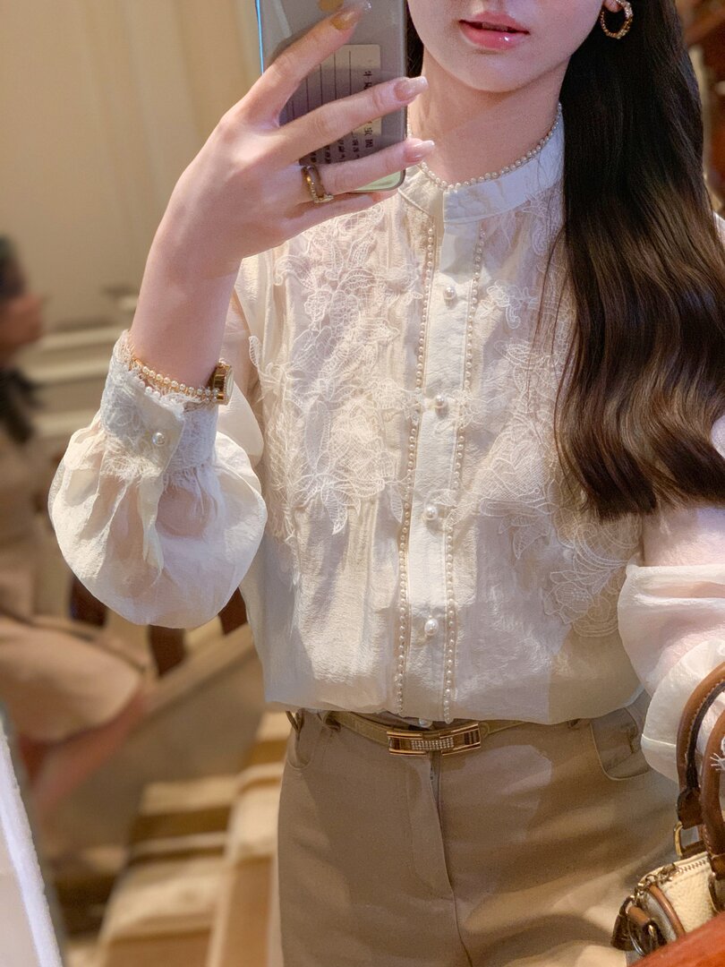 Woman wearing a white lace embroidered blouse with pearl details