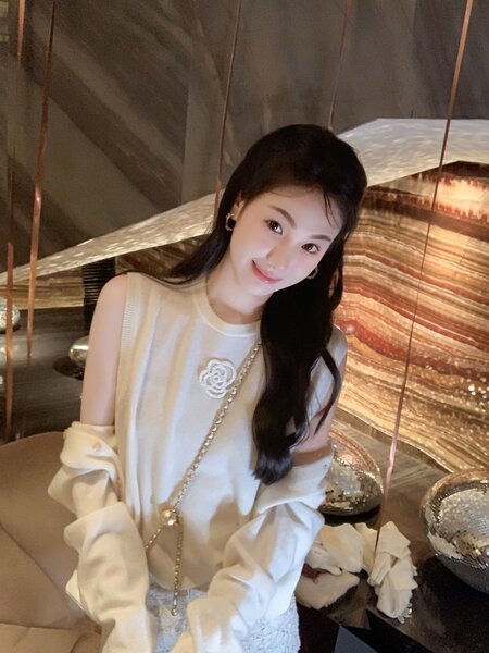 White sleeveless fashion top with decorative flower brooch worn by a model