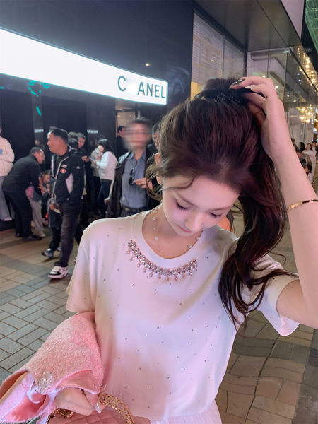 Woman wearing a white embellished short-sleeve top with pink accessories at night