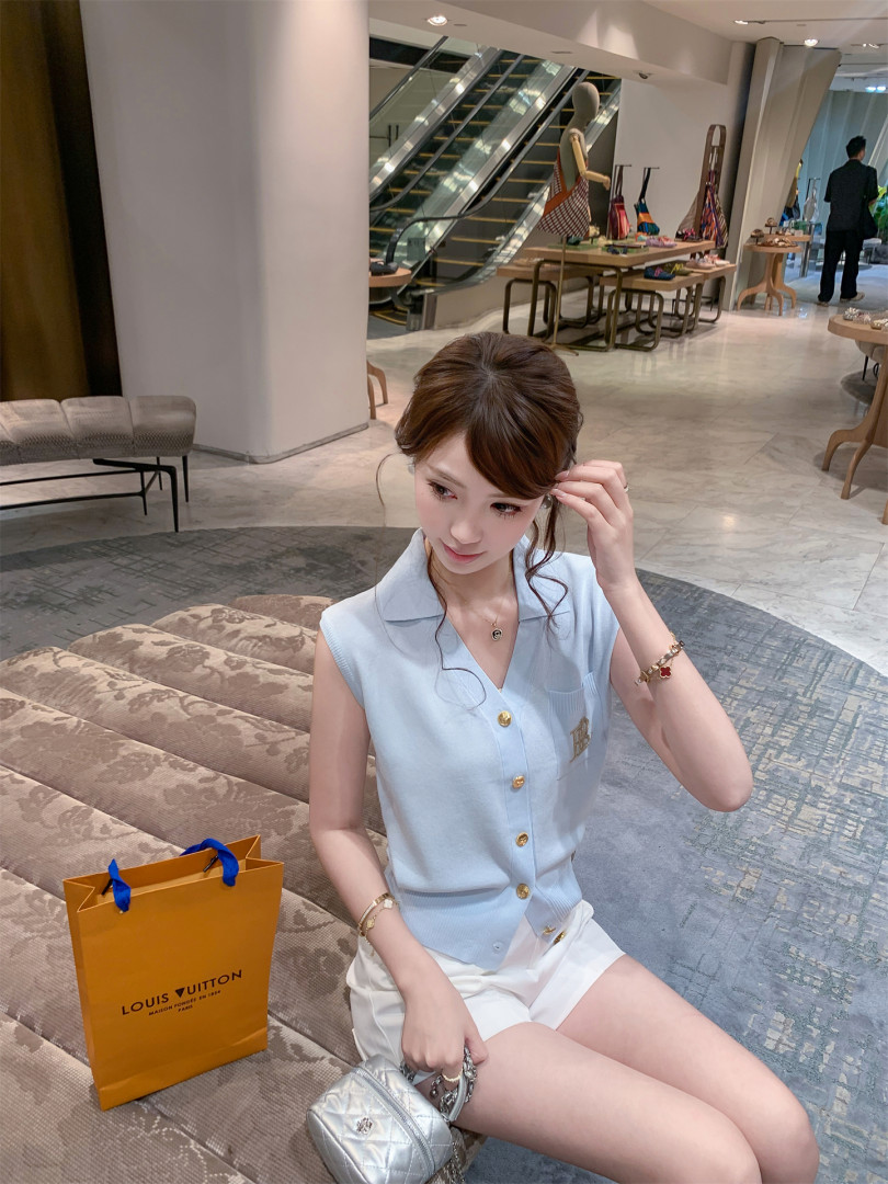 Woman wearing a light blue sleeveless button-front top with white shorts
