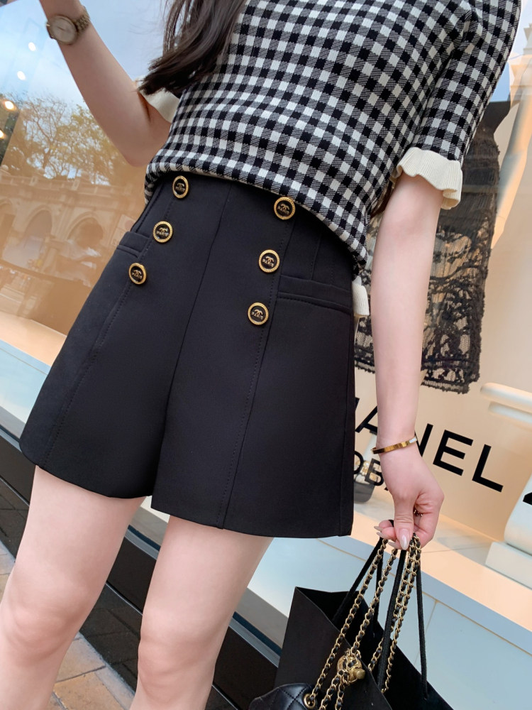 Black high-waisted button-front shorts worn with a black-and-white checkered top