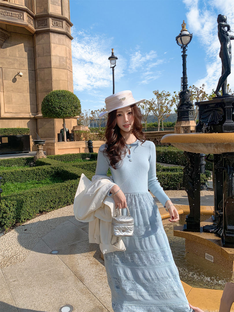 Woman wearing a light blue long dress and white hat outdoors