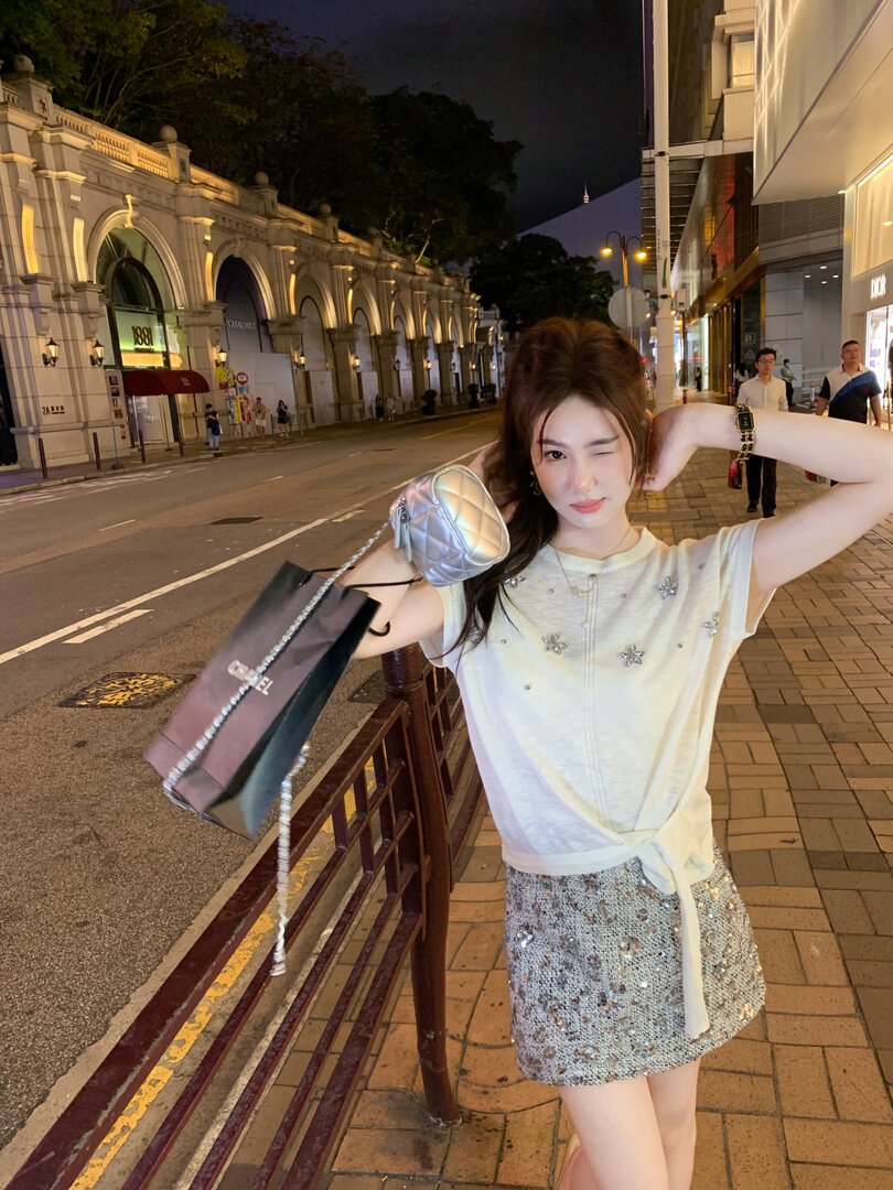 Woman wearing a white embellished top and silver sequin mini skirt at night