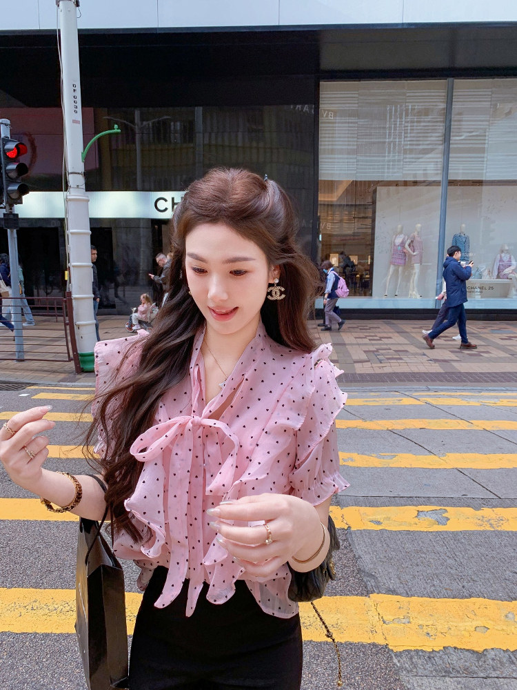 Pink polka dot ruffle blouse worn by a woman outdoors