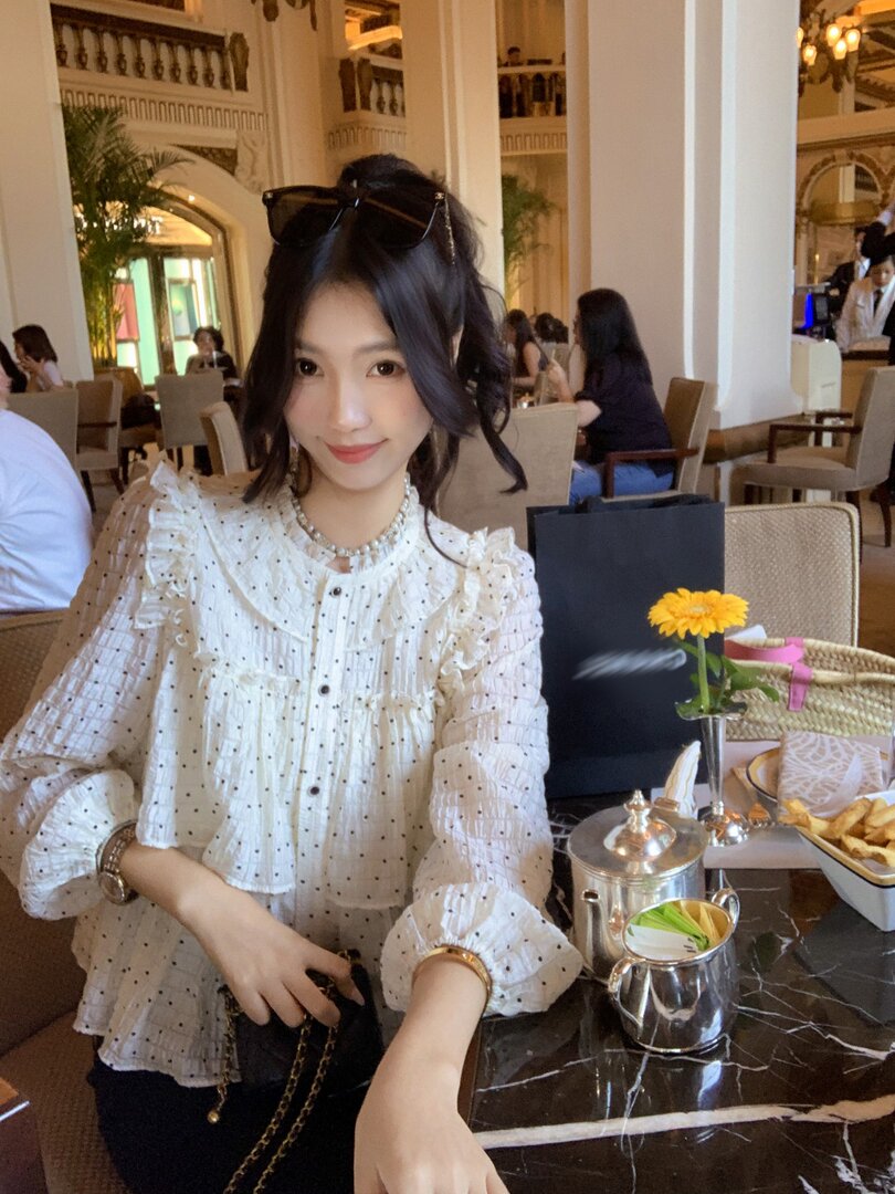 Woman wearing a white polka dot ruffled blouse at a restaurant