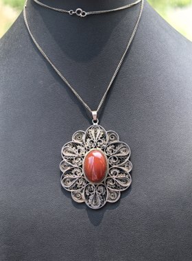 它是一枚老银花丝镶嵌天然红玛瑙吊坠