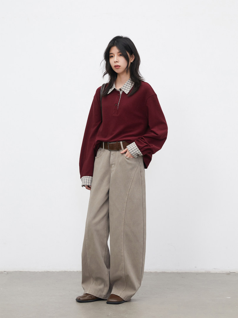 Model wearing a burgundy layered sweater with plaid collar and wide-leg beige pants