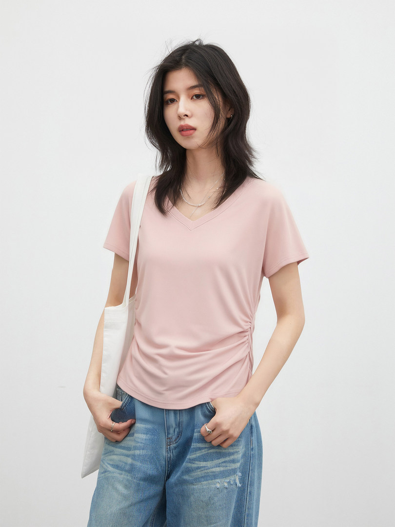 Model wearing a light pink V-neck short sleeve top with blue jeans