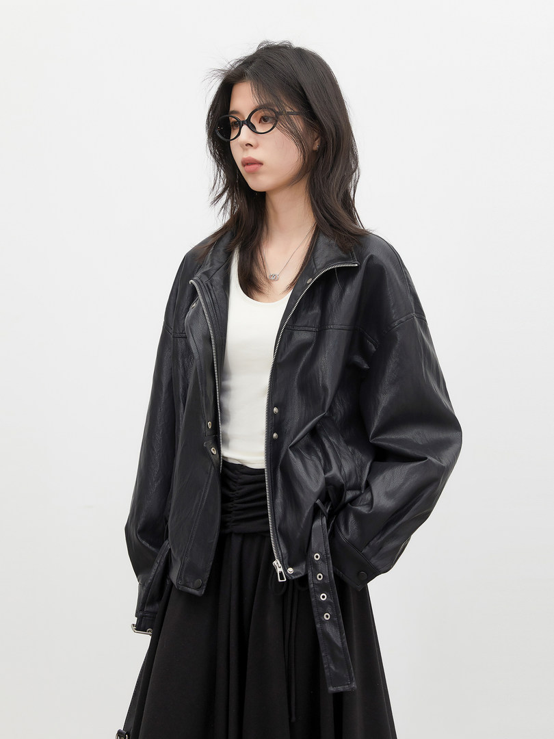 Model wearing a black leather jacket over a white top and black skirt