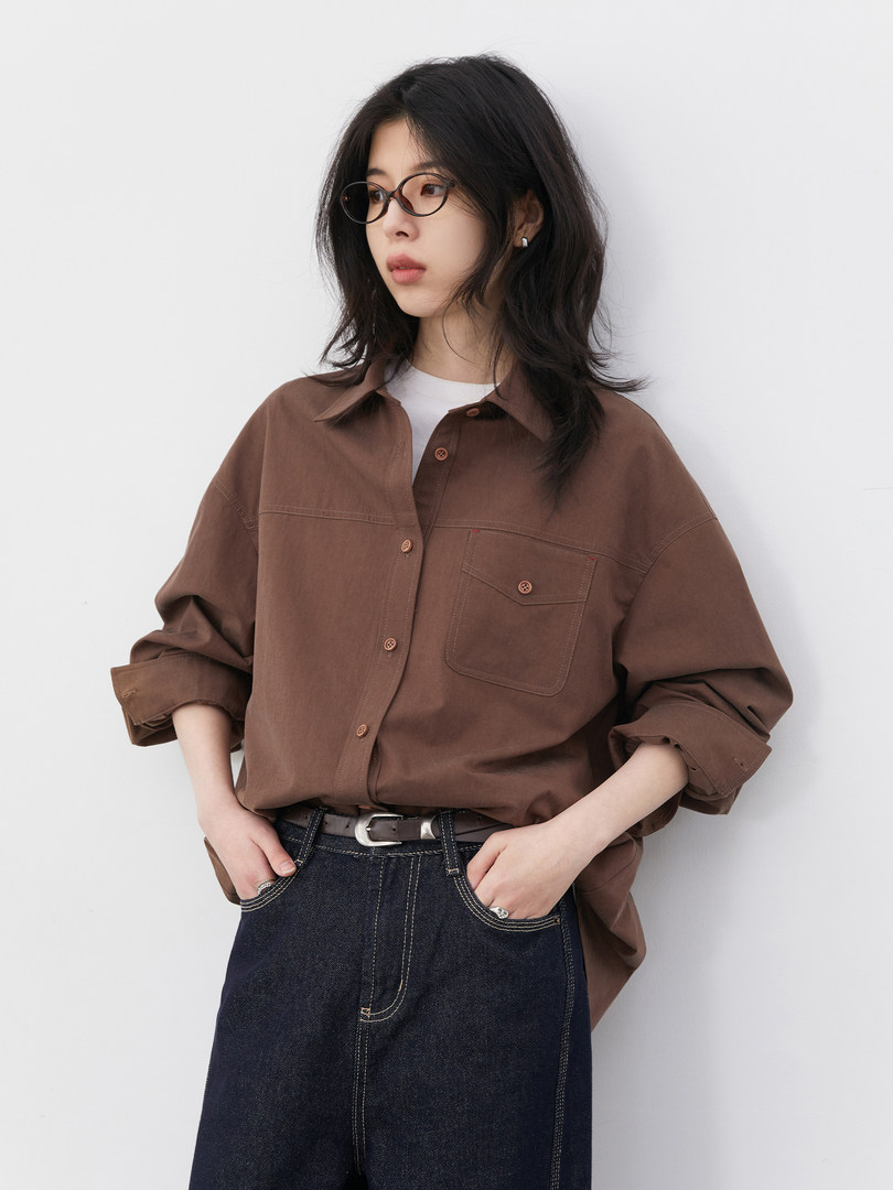 Model wearing a brown oversized button-up shirt with a dark denim skirt