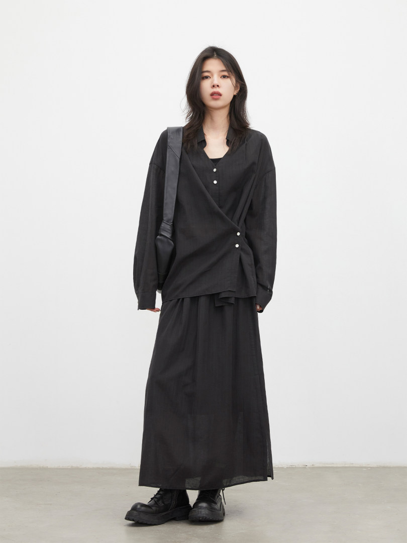 Model wearing a black long-sleeve wrap top and long skirt with black boots