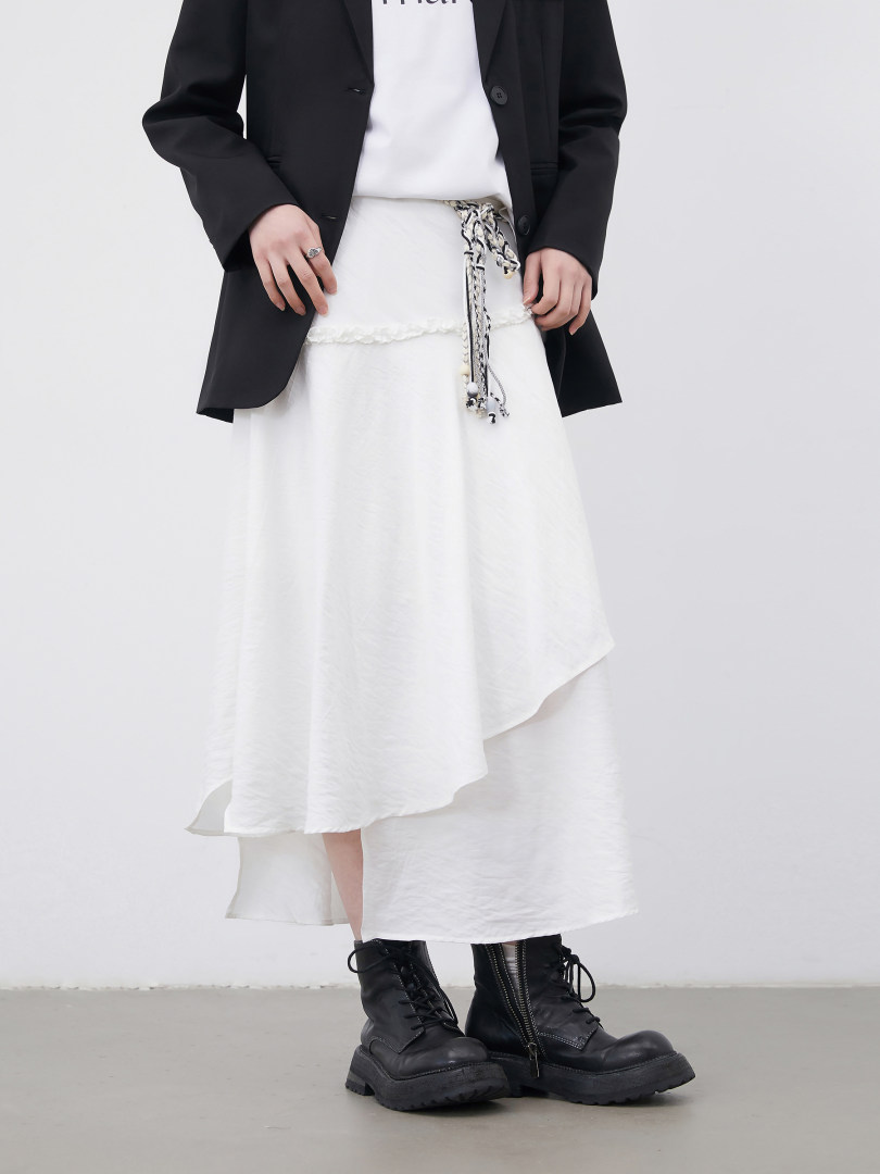 Model wearing a black blazer over a white asymmetrical skirt with black combat boots