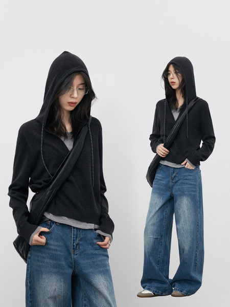 Model wearing a black hooded knit sweater with wide-leg blue jeans