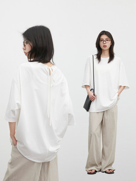 Model wearing a white oversized T-shirt with beige wide-leg pants