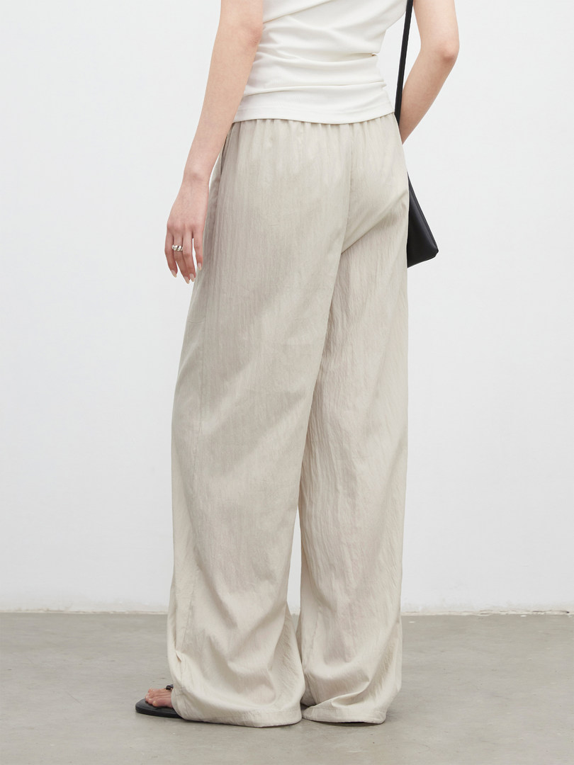 Model wearing beige wide-leg pants with a white top against a plain background