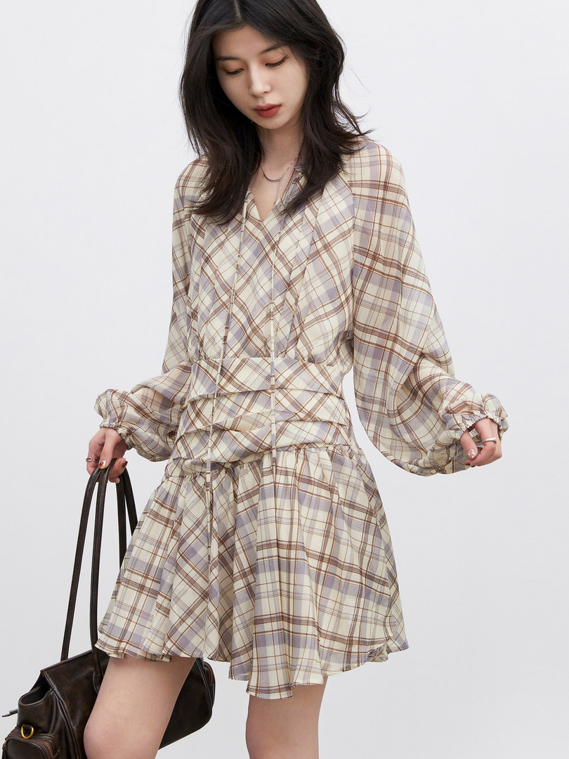 Model wearing a plaid long-sleeve mini dress with a matching cinched waist
