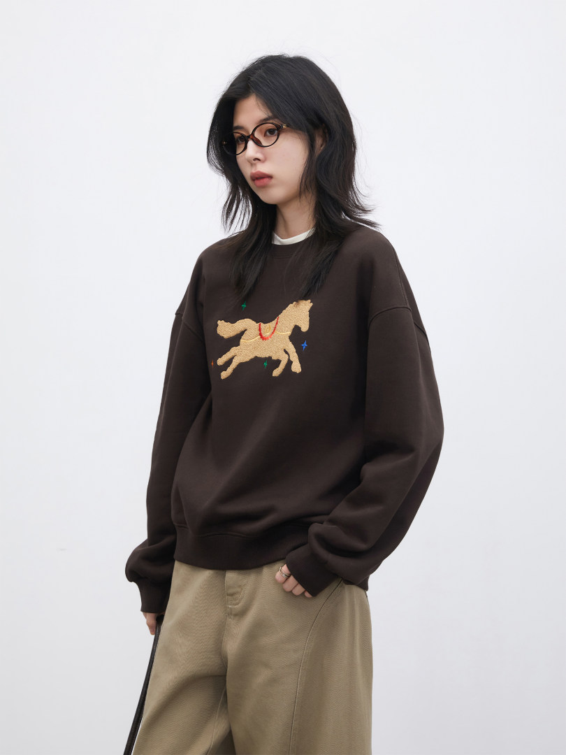 Model wearing a dark brown graphic sweatshirt with beige pants