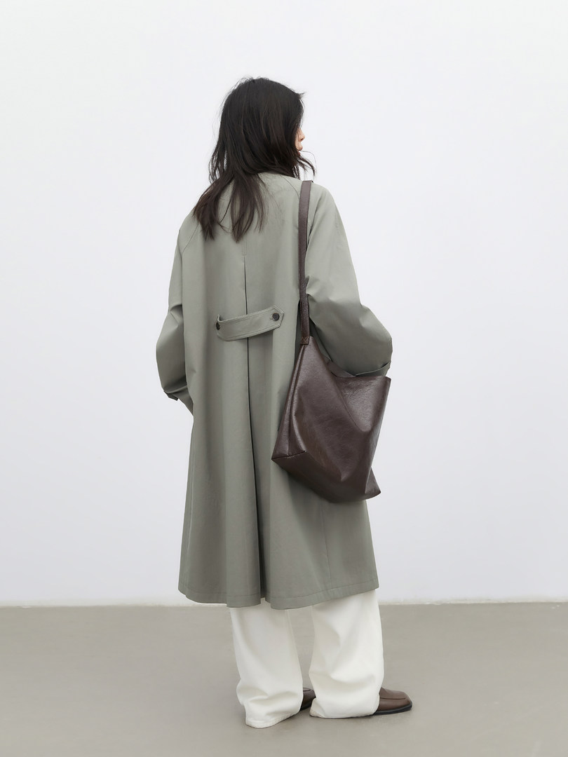 Model wearing a light gray long coat with a brown shoulder bag