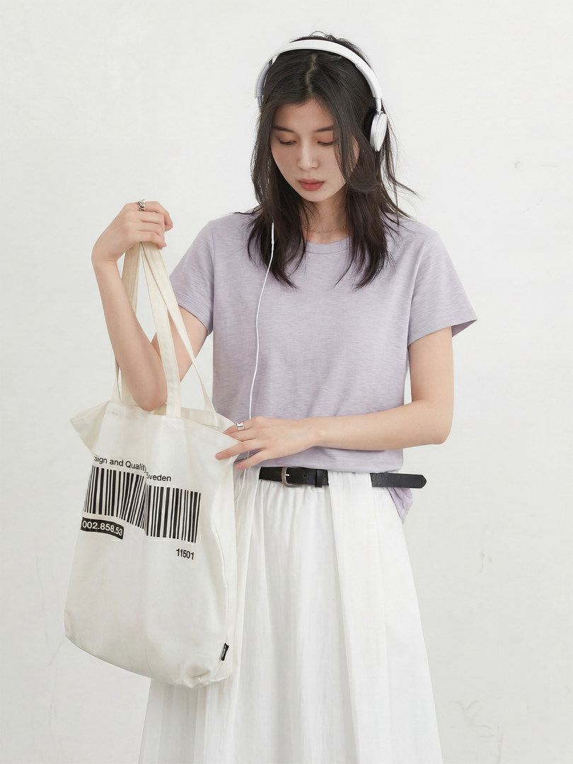 Woman wearing a light purple T-shirt and white skirt, holding a cream tote bag